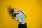 🥇 Image of Woman listening to music with headphones on yellow ...
