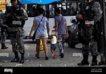 Residents walk past Brazilian Public-Safety National Force policemen as ...