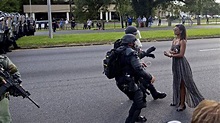 Photo of police in riot gear arresting protester in a dress strikes ...