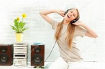 Young beautiful woman listen music with headphone in a living room ...