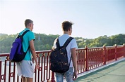 Premium Photo | Two teenage boys with backpacks walking on bridge, back ...