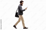 Stockfoto Man walking and looking into a mobile phone | Adobe Stock