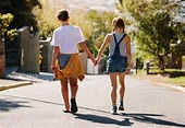 Boy and girl walking on an empty road together. Kids in love walking on ...