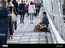People walking past a homeless man begging on Hungerford Bridge in ...
