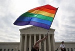 A supporter of same-sex marriage waving a rainbow-colored flag outside ...