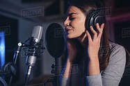 Close up of female vocal artist singing in a recording studio. Woman ...