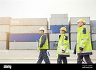 Dock workers walking along cargo containers at shipyard Stock Photo - Alamy