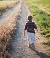 Young boy walking on rural path - Stock Photo - Dissolve