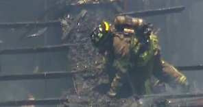 Watch: Firefighter falls through roof of burning building
